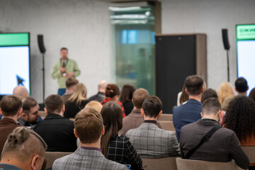 Fototapeta premium Business conference audience listens to speaker during corporate seminar, networking and professional presentation. Focus on listening, learning, and communication.