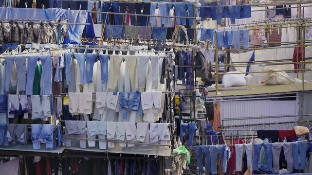 Daylight outdoor wide shot of a series of clothes hung on the lines, bamboo sticks in the Dhobi Ghat, one of the largest open-air manual laundries in the world, in the downtown of the financial capita