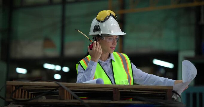 Railway engineer studies blueprints and inspect locomotives in a train maintenance depot, wearing safety helmets and reflective vests in an industrial workshop.

