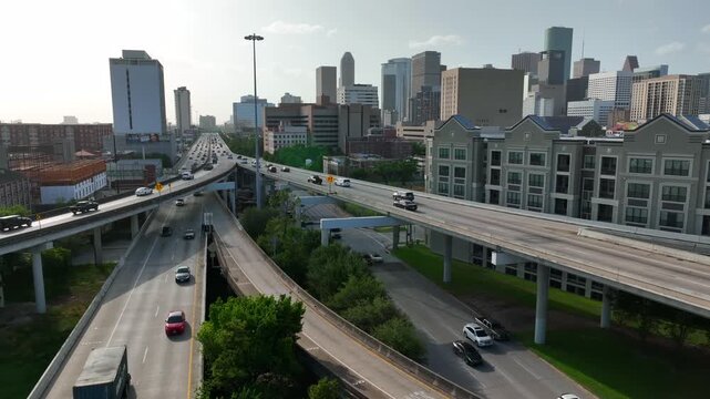 Aerial view of busy highway intersection in Houston downtown with high rise office buildings and urban traffic flow during golden hour.