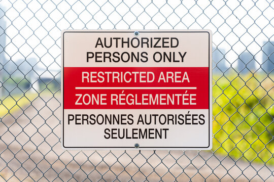 Bilingual Restricted Area Sign on Chain Link Fence