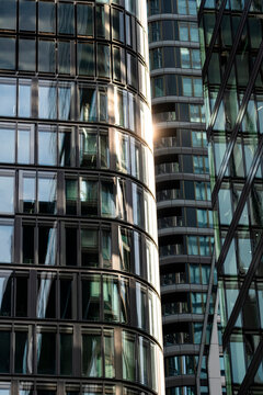 Sunlight moves over a curved glass tower, placing modern skyscraper architecture, reflections, windows and office exterior in vertical depth