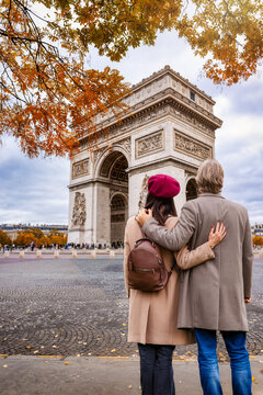 A romantic tourist couple looks at the Arc de Triomphe in Paris, France, during their city sightseeing trip
