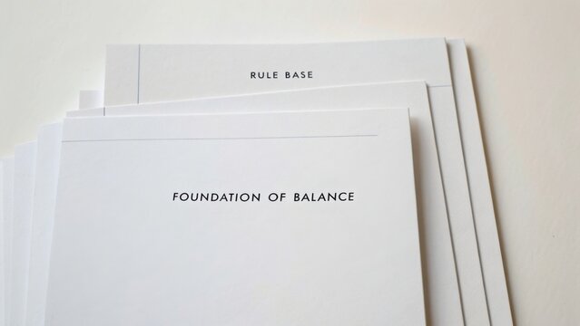 Minimalist Setup of White Papers Highlighting Rule Base and Foundation of Balance on a Clean White Background