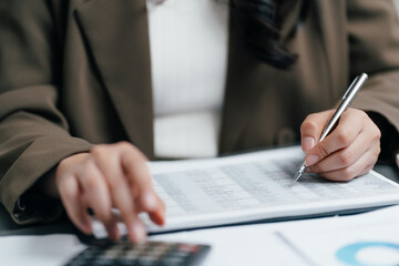 Naklejka premium Accountant using pen and calculator to review a financial data report on office desk, businesswoman auditing business tax, budget or investment profit