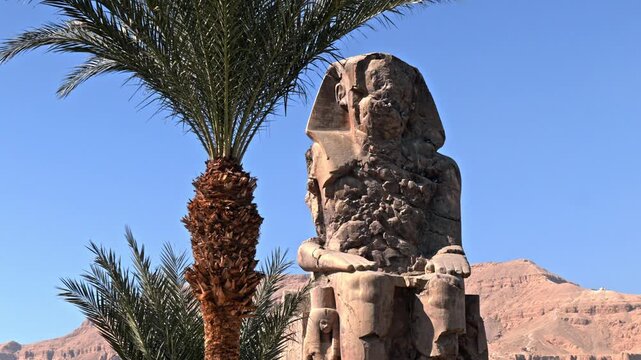 An eye-level shot capturing one of the two massive quartzite sandstone statues known as the Colossi of Memnon in Luxor, Egypt.