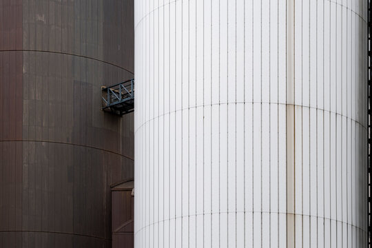 Cylindrical facade detail contrasts white and brown panels in modern architecture as vertical lines and exterior cladding reveal surface texture