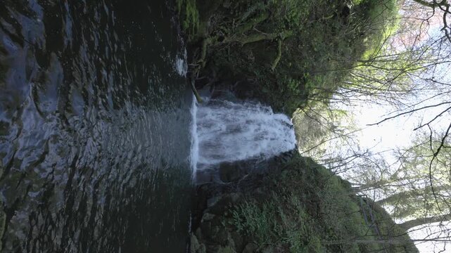 vertical wide-angle shot of Gleno waterfall cascading through the valley