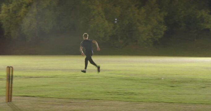 Bowler adjusting runup on pitch delivering chasing, fielder fetching ball throwing to stumps