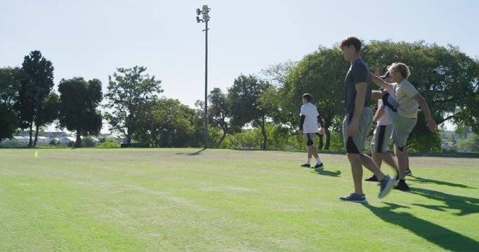 Walking male teammates stretching and warming up before practice