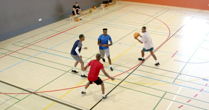 Diverse male friends tossing ball at gym running pick-roll, intercepting pass, shooting