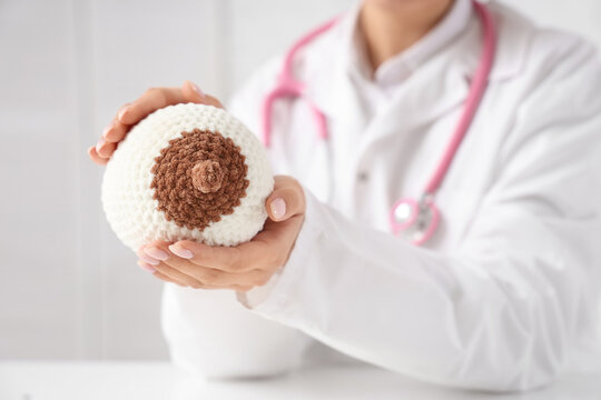 Female doctor with knitted breast model in clinic, closeup