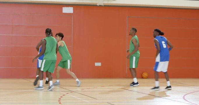 Inbounding pass, diverse male team dribbling, attacking layup on gym court, contesting rebound