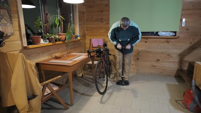Cyclist inflating bicycle tire with floor pump before outdoor cycling, home maintenance routine preparing equipment for upcoming ride