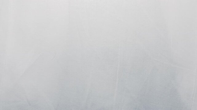 white linen fabric ripples gently under soft natural studio lighting in a serene cinematic tracking shot