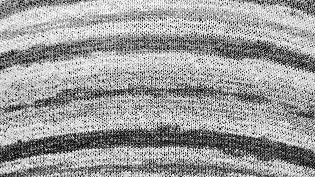 monochrome knitted fabric ripples smoothly during a macro tracking shot revealing detailed zebra stripe texture
