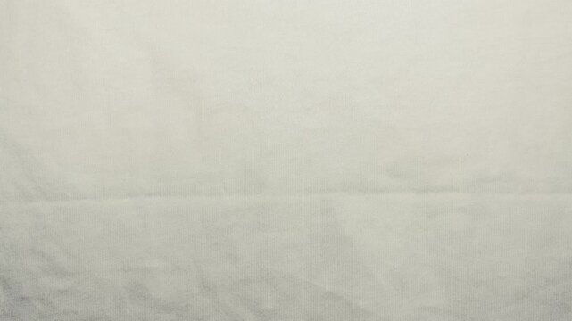 white linen fabric ripples gently in macro slow motion showcasing organic textile weave texture under bright soft light