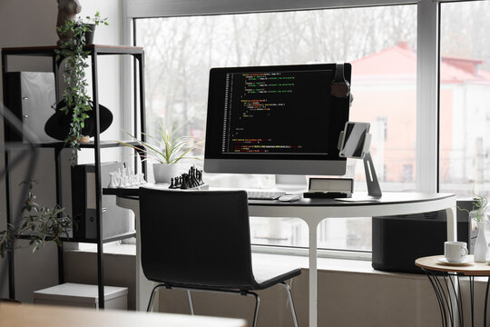 Programmers desk with computer monitor and chessboard in office
