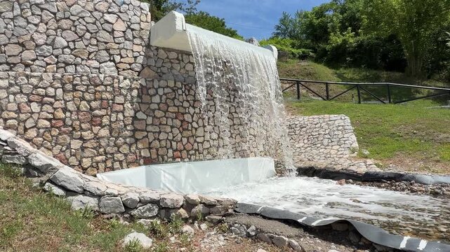 A video of an outdoor backyard waterfall designed as a decorative landscape water feature.