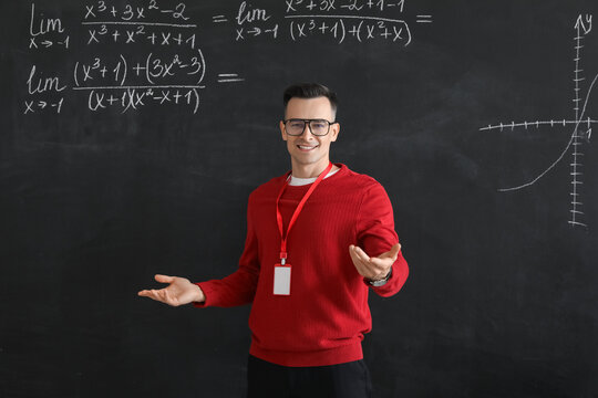 Male Math teacher conducting lesson near blackboard in classroom