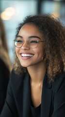 Fototapeta premium Happy young businesswoman with curly hair smiling during a collaborative office team meeting