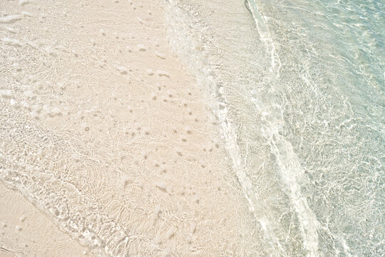 Beautiful bright clear sea with waves splashing and tropical beach sand close-up
