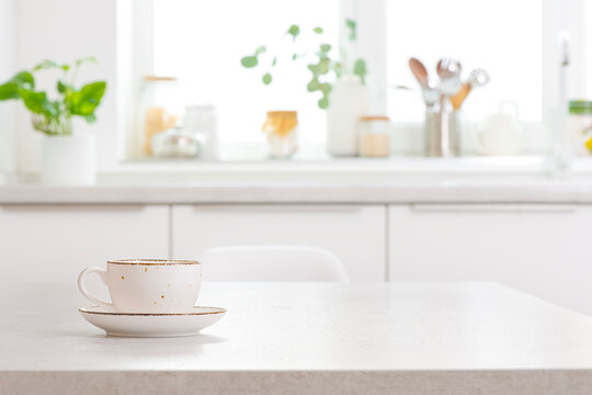 Saucer with cup on table in modern kitchen interior as blurred background