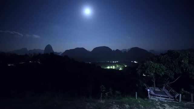 Slow motion panoramic view of moonlit karst mountains tropical island and Phang Nga bay and valley village at night panning shot.