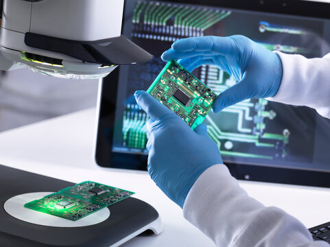 Engineer using a 3d stereo microscope for quality control in the manufacturing of circuit boards for the electronics industry