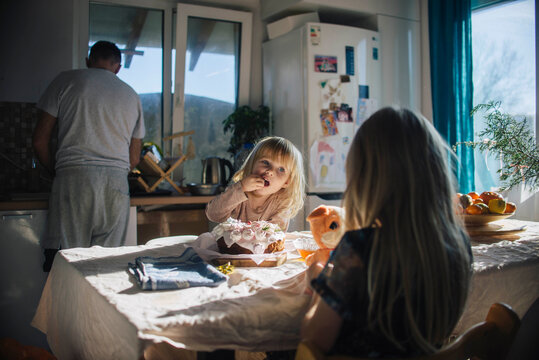 Girl eating cake in kitchen near family at home