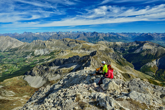Couple sitting on Pic de Bure summit enjoying the landscape