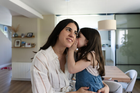 Mother and daughter whispering a secret at home