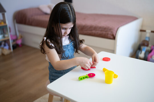 Focused girl playing with playdough at home