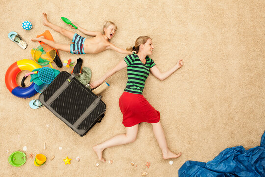 Woman and child playing with beach gear and luggage in studio setting