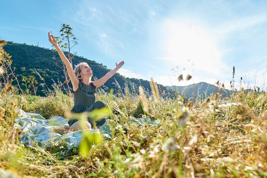 Happy woman sitting in a spring flower meadow enjoying freedom