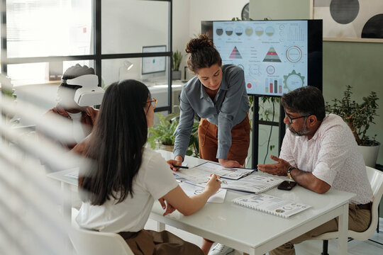 Colleagues discussing a project in an office with VR glasses and data charts