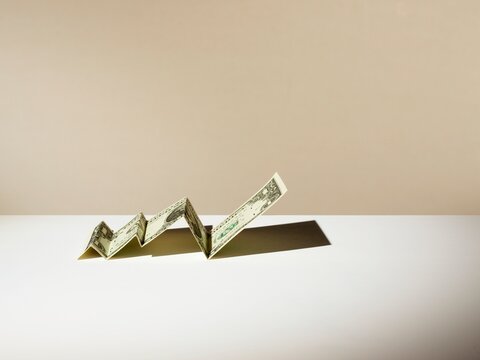 Folded US dollar note forming a rising line graph showing progress