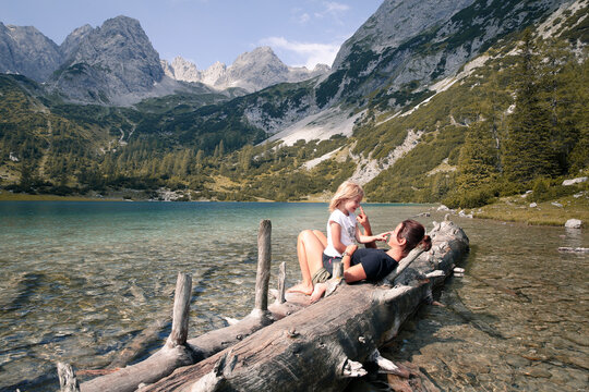Austria, Tyrol, playful mother and daughter on tree trunk at lake Seebensee