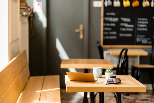 Book and camera on wooden table in modern coffee shop