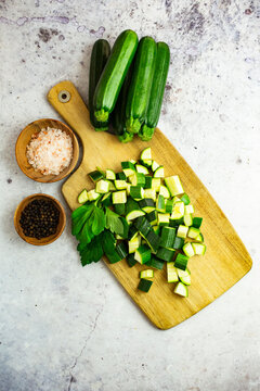 Studio shot of chopped parsley and zucchinis and wooden bowls with black peppercorns and Himalayan salt