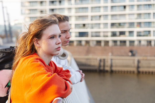 Friends lean on river railing in urban HafenCity