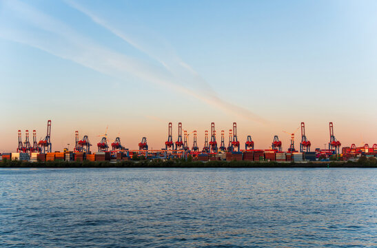 Hamburg harbor industrial skyline with container cranes at sunset