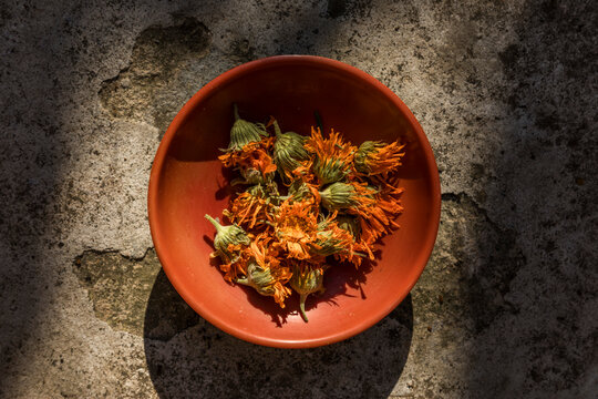 Top view of dry calendula flowers in a terracotta bowl outdoors