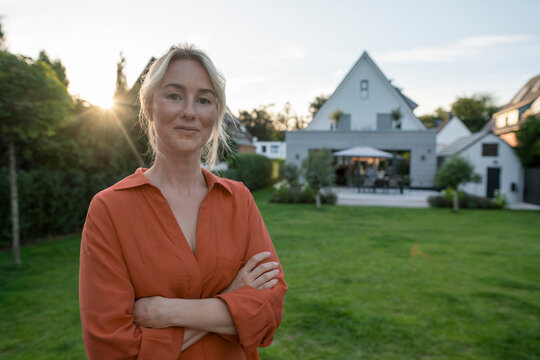 Smiling woman with arms crossed in back yard