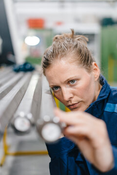 Young woman working as a skilled worker in a high tech company, checking steel rods