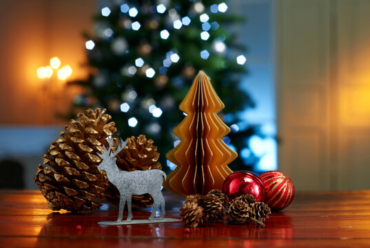 Close-up of various decorations on wooden table with illuminated Christmas tree in background at home
