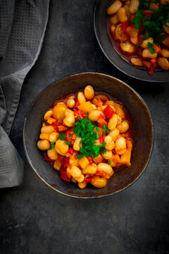 Broad bean stew with tomato and bell pepper in black bowl