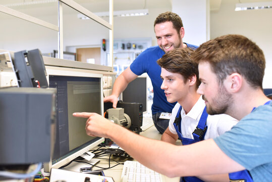 Technical instructor and students looking at computer screen