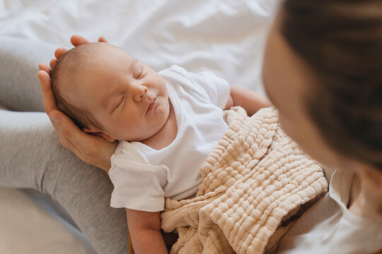 Cute newborn baby sleeping in mother's arms at home