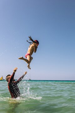 Father throwing daughter in the air while swimming in the summer sea